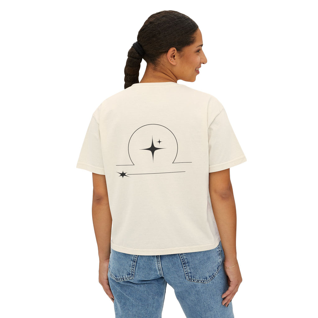 Person wearing a Beige t-shirt with a minimalist Libra zodiac design in orbital line-art in the back